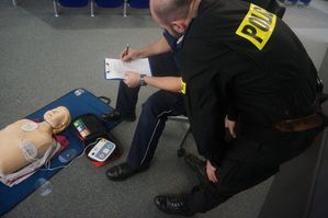 Zdjęcie kolorowe. Sędzia konkurencji ocenia funkcjonariusza po zakończeniu rywalizacji udzielania pierwszej pomocy.