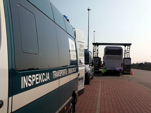 Pojazdy Wojewódzkiego Inspektoratu Transportu Drogowego z Katowic. W tle policjant sprawdza autobus.