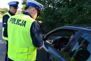 Policjant rozmawia z kierowcą auta podczas akcji Bezpieczny weekend - ostatni weekend wakacji.