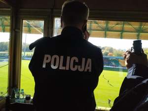 Policjant podczas zabezpieczenia meczu spogląda przez okno na stadion