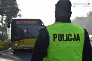 policjant podczas akcji Znicz 2019. W tle autobus jadący na cmentarz.