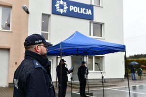 Umundurowany policjant stojący przed budynkiem posterunku