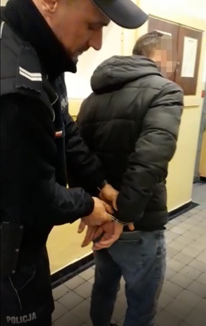 Policjant zakłada kajdanki zatrzymanemu