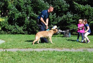 Policyjny przewodnik psa wr5az  z czworonogiem bawią się z dziećmi.