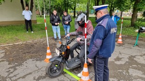 Policjant i uczestnik turnieju podczas konkurencji jazdy motorowerem