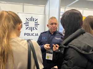 Na zdjęciu policjant w trakcie targów pracy podczas rozmowy z osobami zainteresowanymi służbą w Policji.