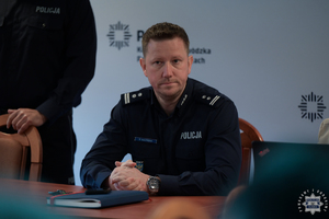 Zastępca Komendanta Wojewódzkiego Policji w Katowicach siedzący za stołem konferencyjnym