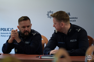 Zastępca Komendanta Wojewódzkiego Policji w Katowicach wraz z naczelnikiem siedzący za stołem konferencyjnym