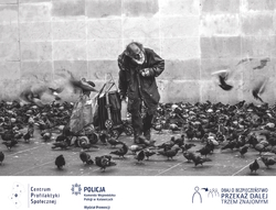 Zdjęcie czarno-białe przedstawiające osobę bezdomną karmiącą gołębie.