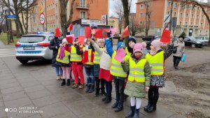 dzicei ze szkoły nr 9 w Częstochowie stoją przed radiowozem trzymając w rękach laurki