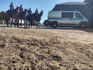 Policyjny radiowóz zaparkowany przy policyjnych jeźdźcach na koniach