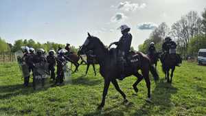 Policjanci uderzają pałkami w tarcze symulując hałas na meczu, policyjne konie i ich jeźdźcy  jeżdżą wokół nich