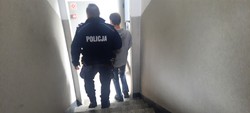 Policjant doprowadza zatrzymanego schodami w dół
