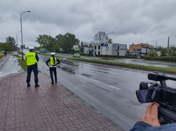 Kamera wysunięta w stronę policyjnego patrolu, który stoi przy drodze