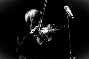 Zdjęcie czarno-białe. Przedstawiające grę na skrzypcach.