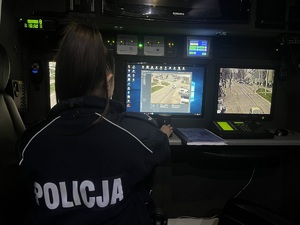 Zdjęcie przedstawia policjantkę siedzącą przed ruchomym stanowiskiem dowodzenia