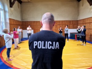 Zdjęcie przedstawia: policjanta podczas ćwiczeń na macie.