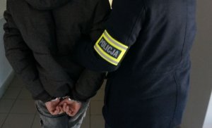 policjant z wydziału krymianlnego podczas prowadzenia zatrzymanego mężczyzny zakutego w kajdanki