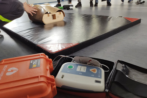 Na zdjęciu widoczne leżące na podłodze AED.