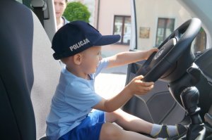 dziecko za kierownicą radiowozu w policyjnej czapce