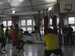 Zdjęcie kolorowe. Zawodnicy w hali sportowej na boisku grają w siatkówkę.