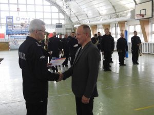 Zdjęcie kolorowe. Zastępca Komendanta Wojewódzkiego Policji wręcza przedstawicielowi drużyny dyplom wyróżnienia.
