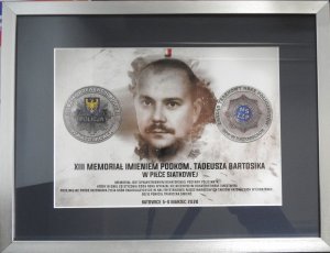 Zdjęcie kolorowe. Tablo pamiątkowe XIII Memoriału im. podkom. Tadeusza Bartosika z jego wizerunkiem.